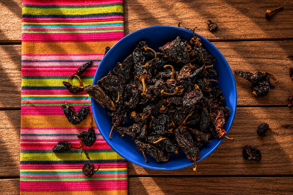 Sušené chilli v modré misce na pruhované mexické látce
